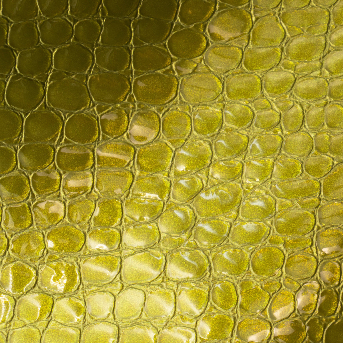 A close-up of a yellow-green textured material with a glossy, reptile-scale pattern.